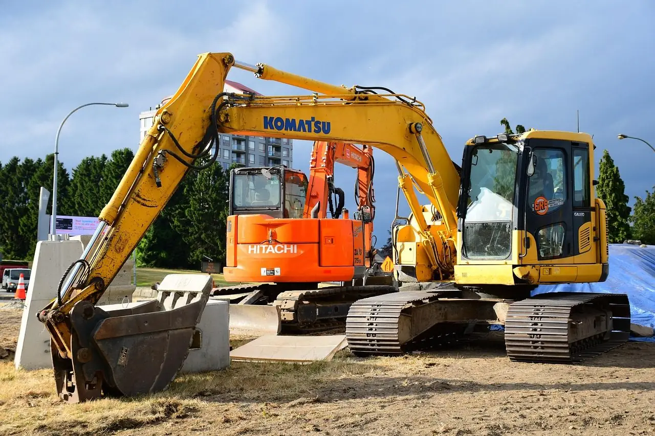 Two excavators parked on grass at a work site