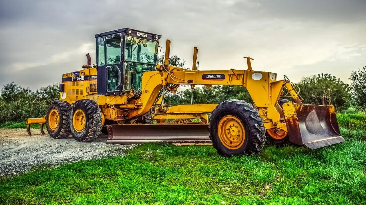 Yellow motor grader parked on grass