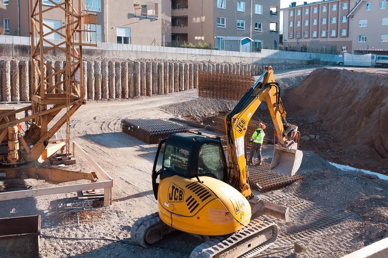 Compact excavator working in a deep construction pit in town