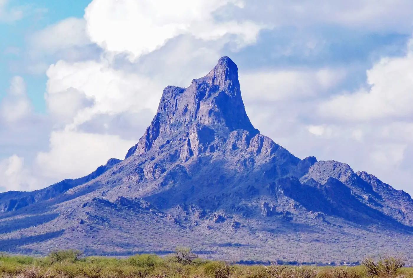 Picacho Peak rising steeply above flat desert under a blue sky